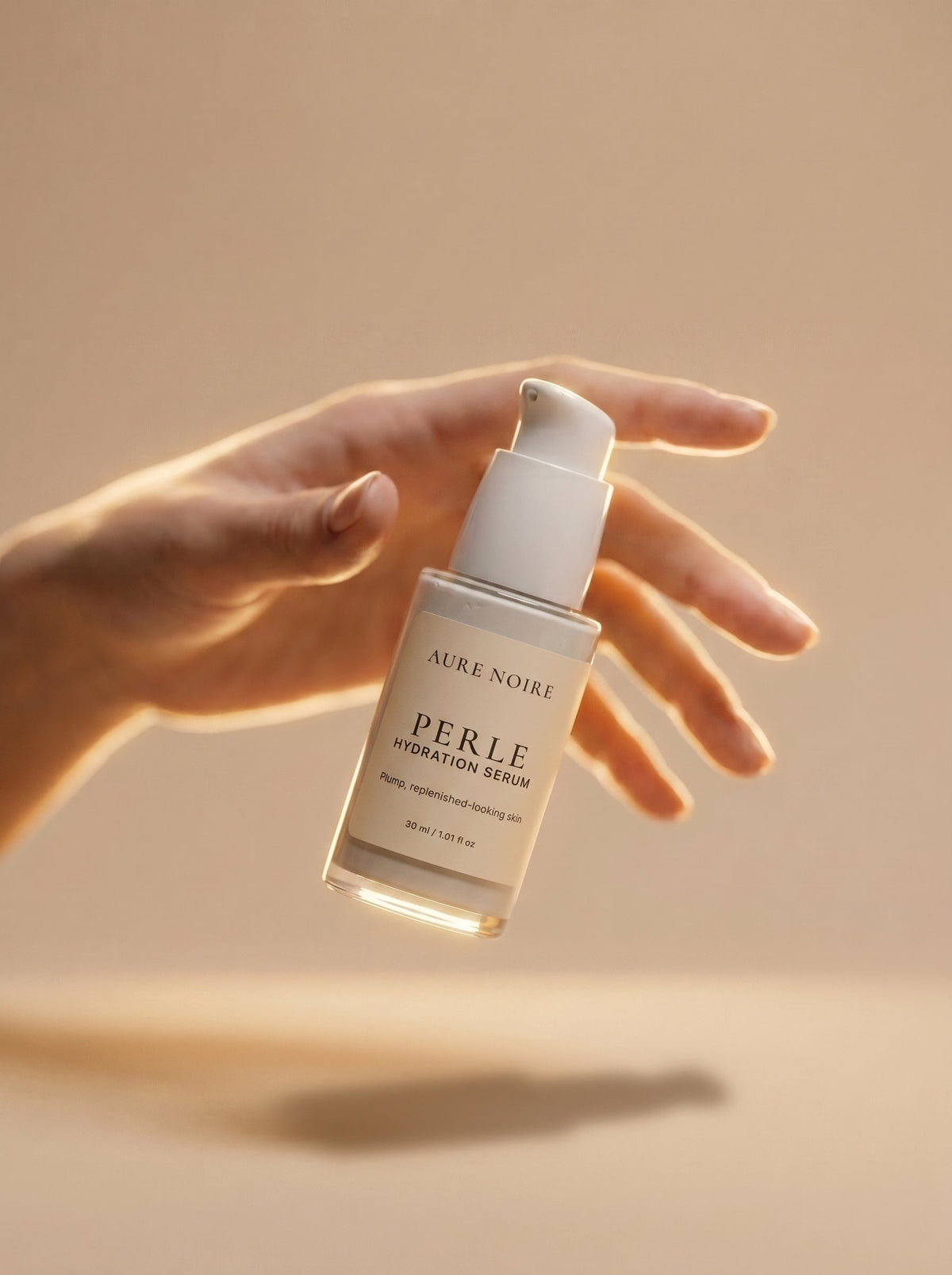A bottle of AURENOIRE PERLE Hydration Serum suspended in front of an open hand